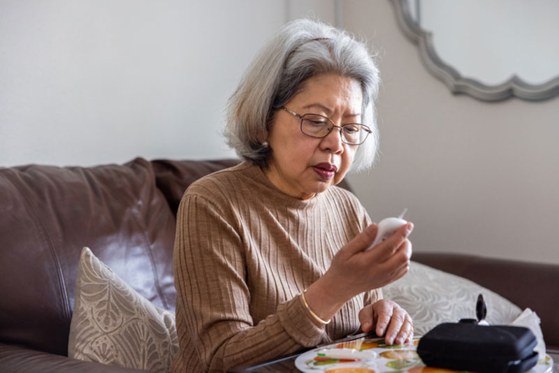 An older woman is keeping diabetes in check by testing her blood glucose.